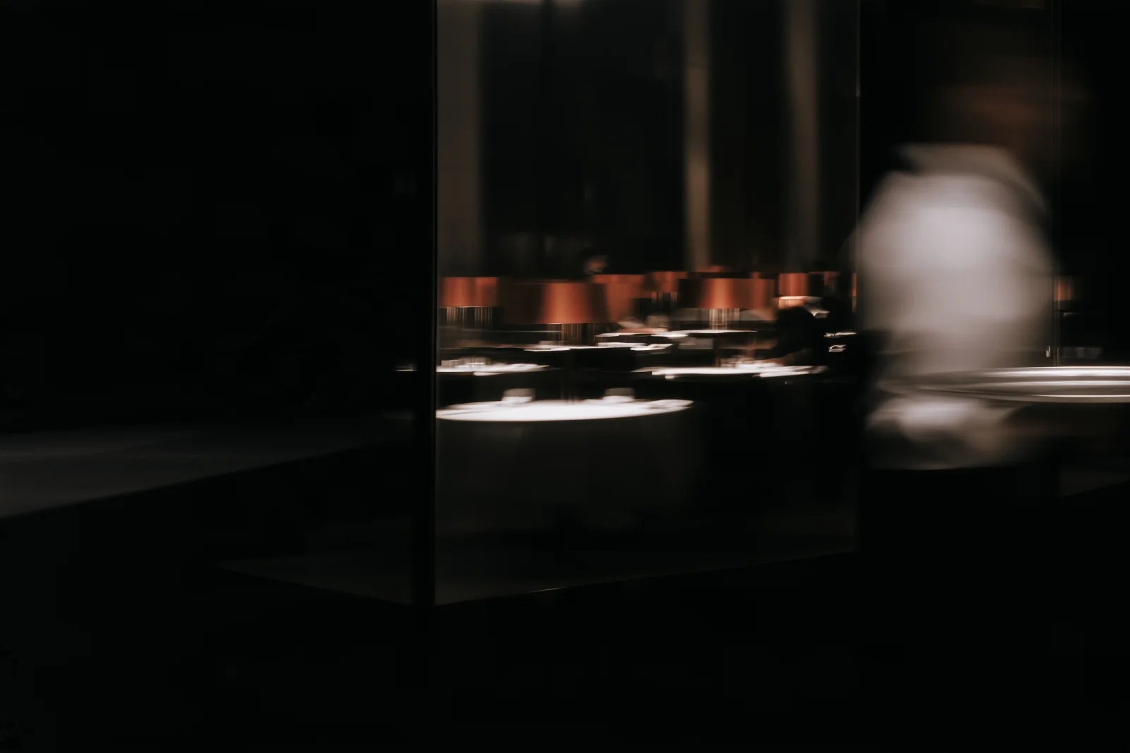 Service in motion among dining room tables and reflections.