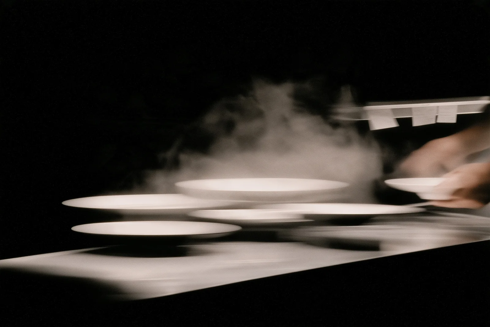 Plates, steel and steam at a kitchen pass during service.