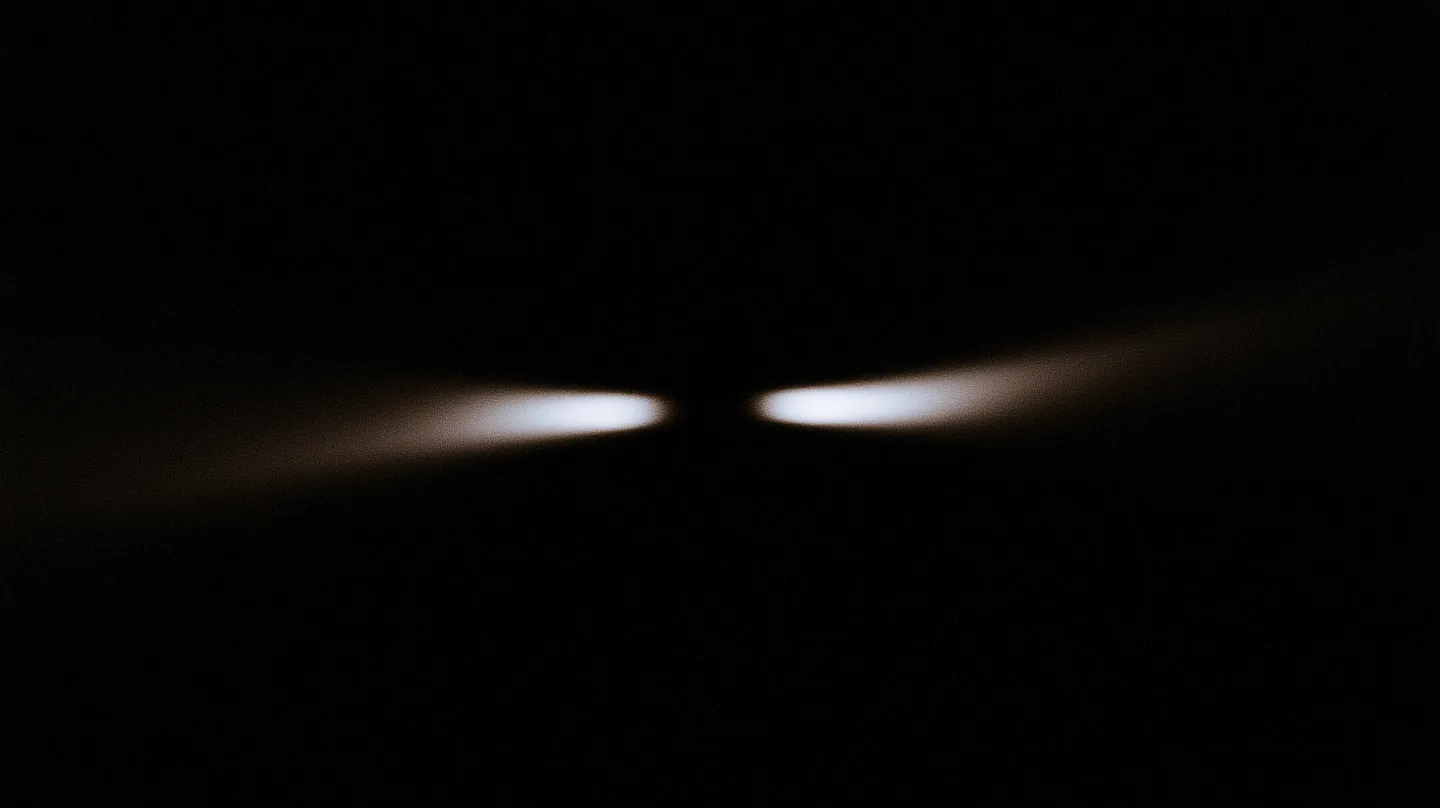 Two restrained fields of light approach one another in darkness.